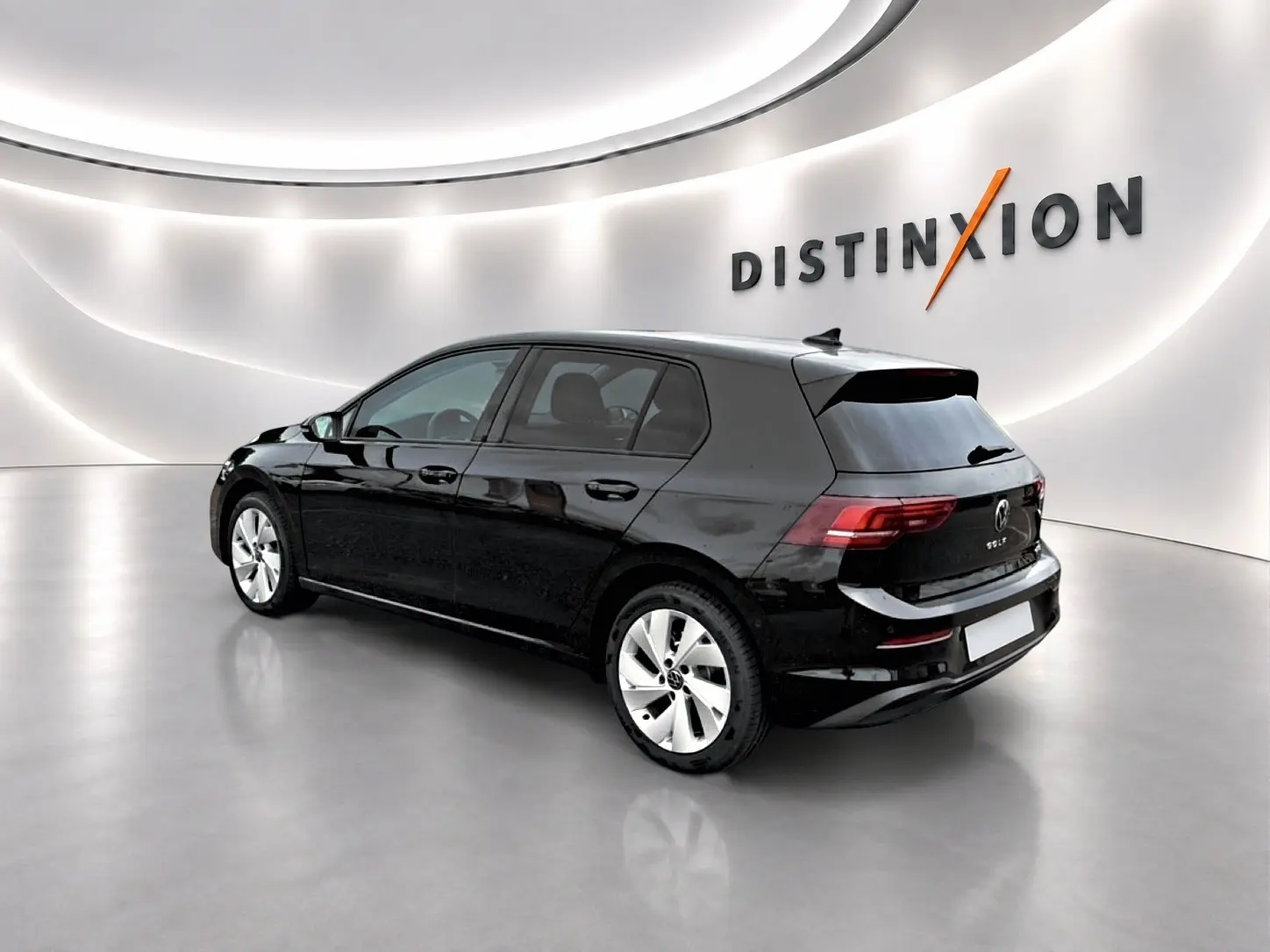 Volkswagen Golf noire vue 3/4 arrière droit dans un showroom lumineux avec jantes alu 17 pouces.