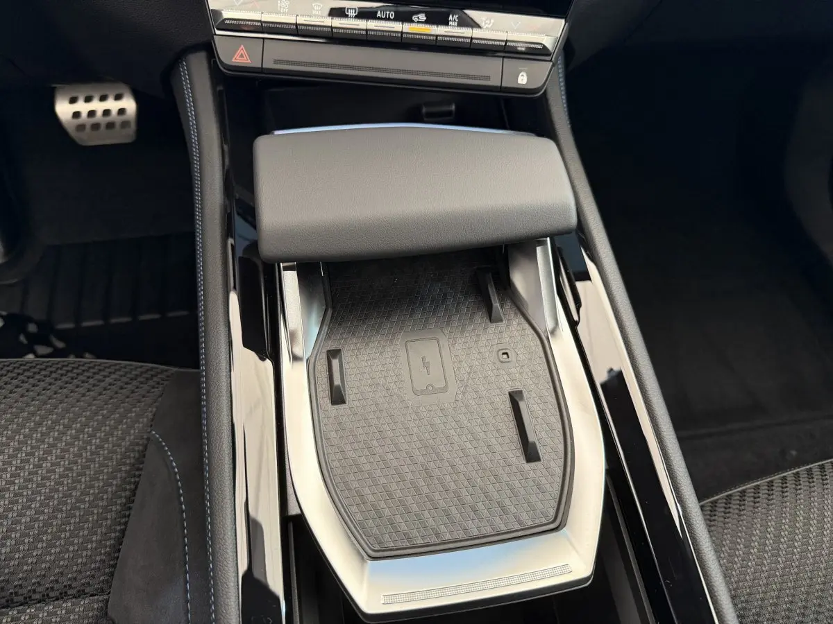 Vue rapprochée de la console centrale noire du Renault Espace 2025 avec zone de recharge sans fil et accoudoir gris.