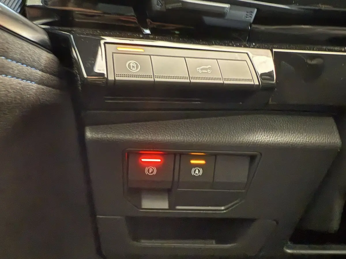 Gros plan sur les commandes de frein de stationnement et démarrage automatique dans l'habitacle noir du Renault Espace esprit Alpine 2025.