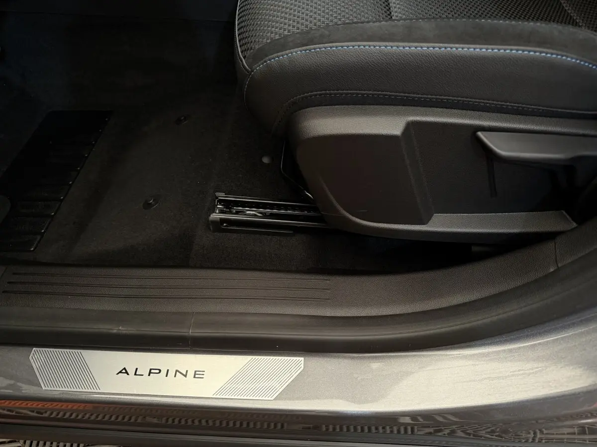Gros plan sur la porte côté gauche d'un Renault Espace gris foncé esprit Alpine, avec seuil de porte marqué "ALPINE" et siège avant.