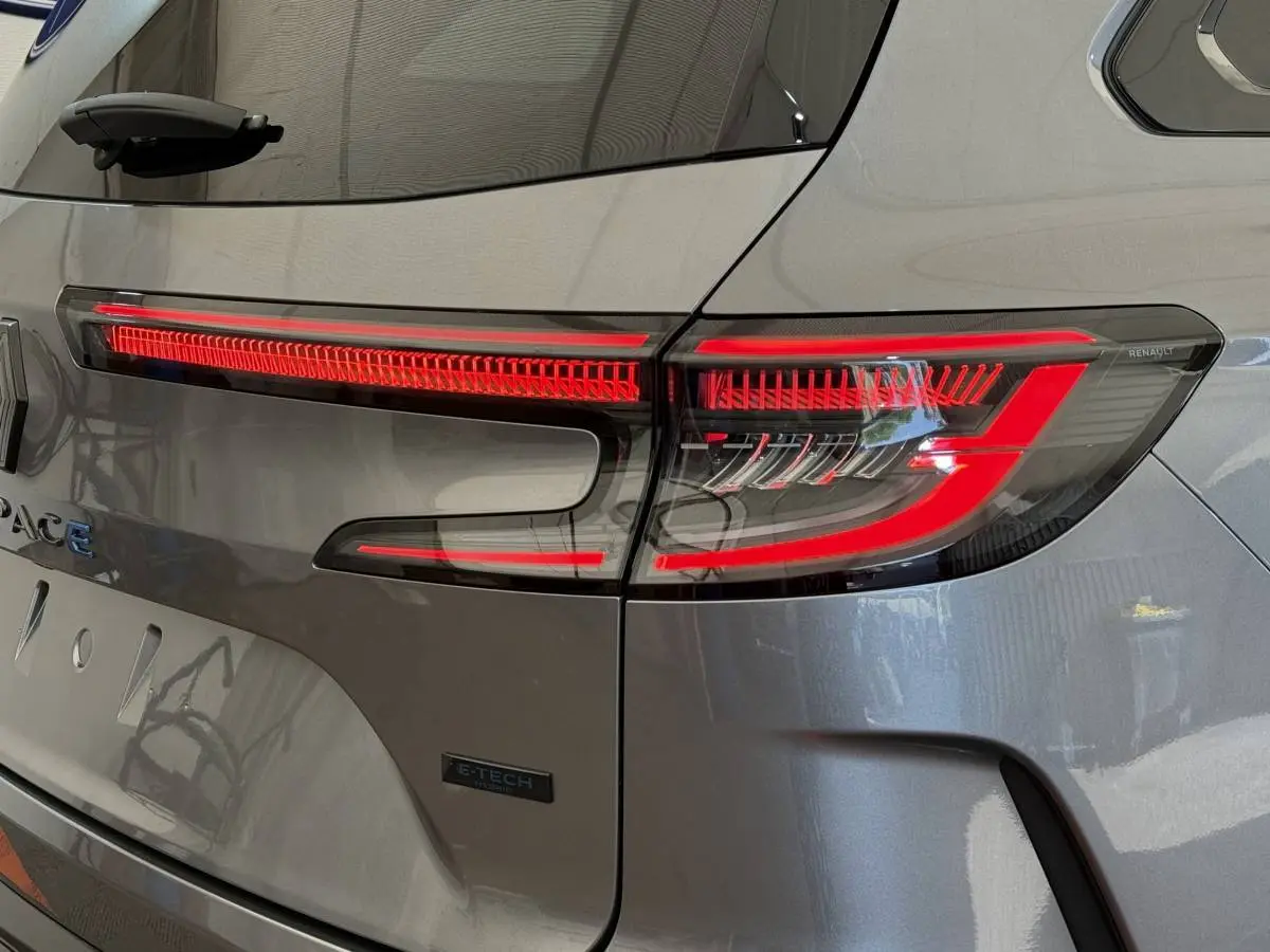 Gros plan sur le feu arrière droit rouge d'un Renault Espace gris foncé hybride E-Tech 2025, avec logo visible.