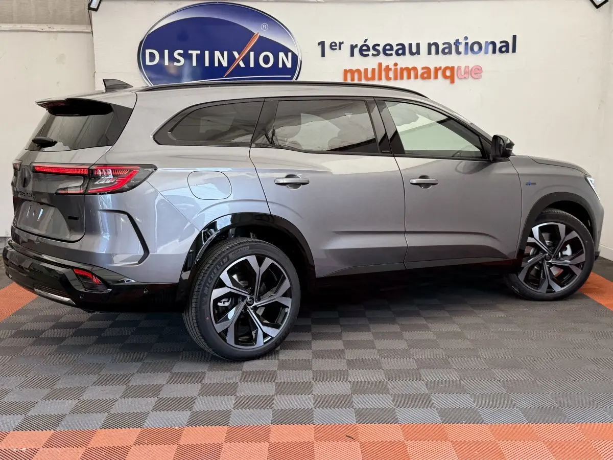 Profil droit du Renault Espace esprit Alpine gris foncé avec jantes noires et toit vitré en intérieur showroom.