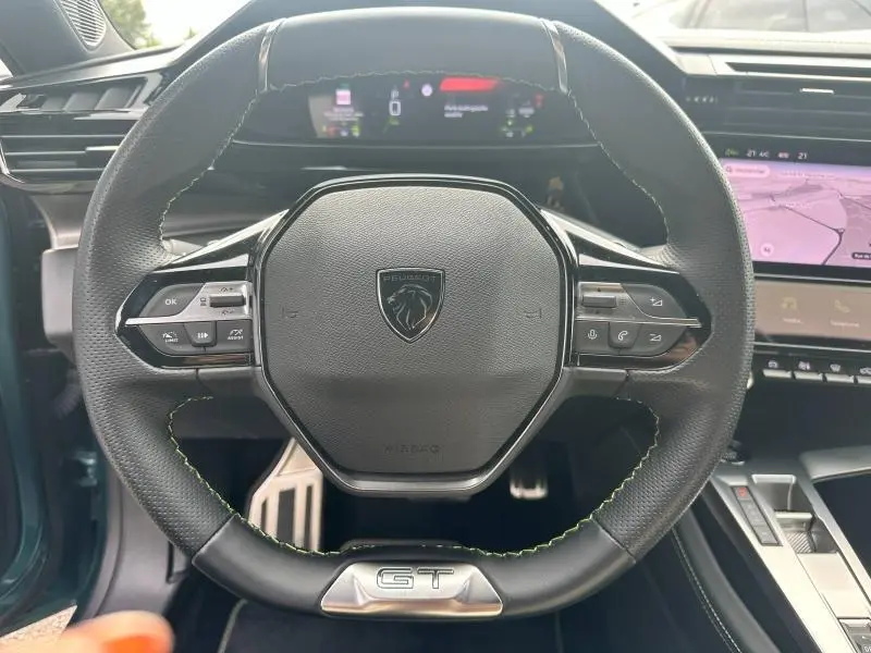 Volant multifonction noir avec surpiqûres vertes et logo GT, tableau de bord numérique et écran tactile Peugeot 308 SW 2023.