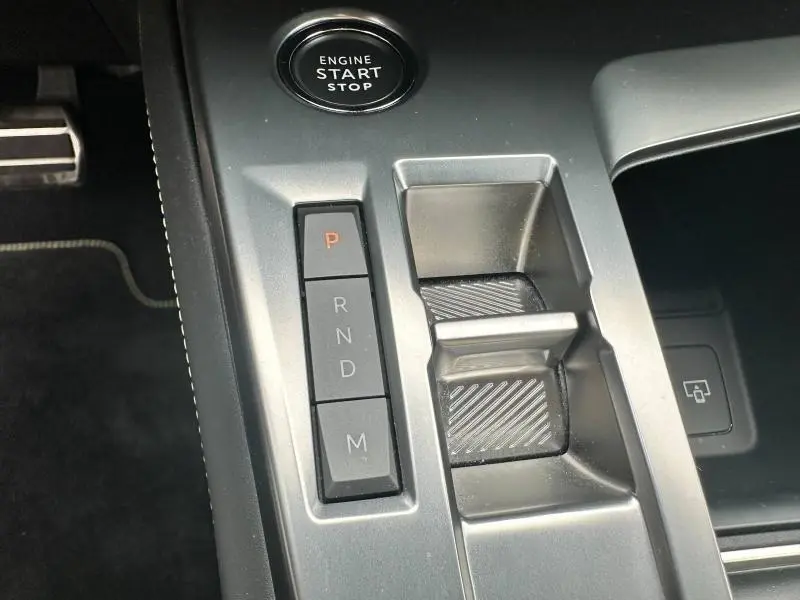Vue rapprochée de la console centrale grise avec bouton start/stop et commandes de boîte automatique de la Peugeot 308 SW 2023.