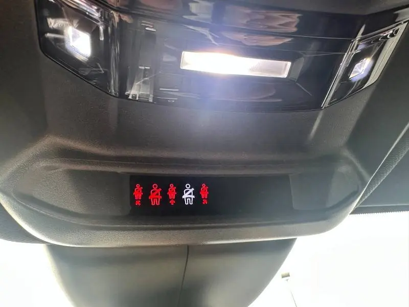 Panneau intérieur de la Peugeot 308 SW 2023 montrant les voyants de ceintures de sécurité allumés sous l'éclairage du plafonnier.