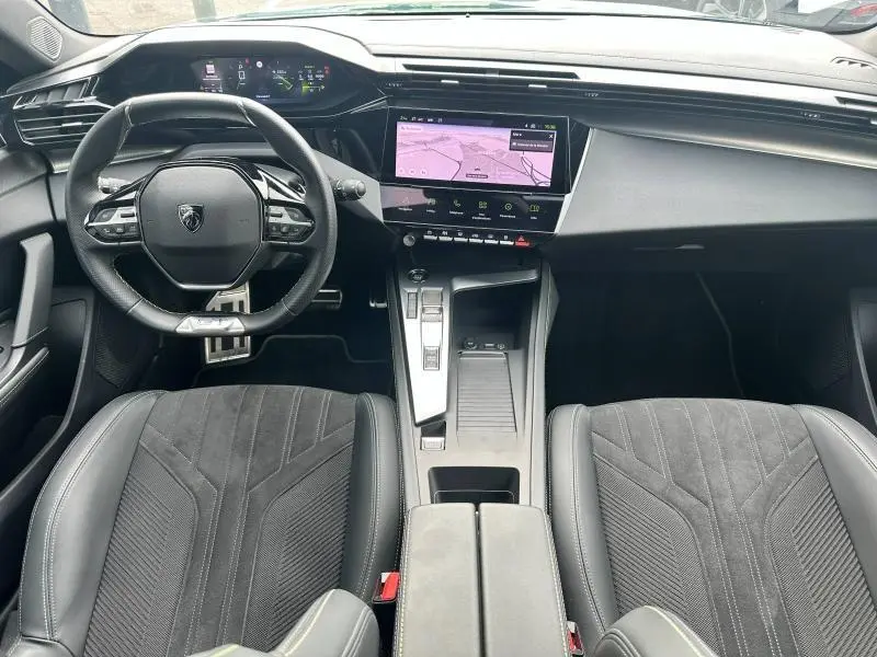 Intérieur noir de la Peugeot 308 SW 2023, vue de face sur le volant compact et l'écran tactile central avec navigation.