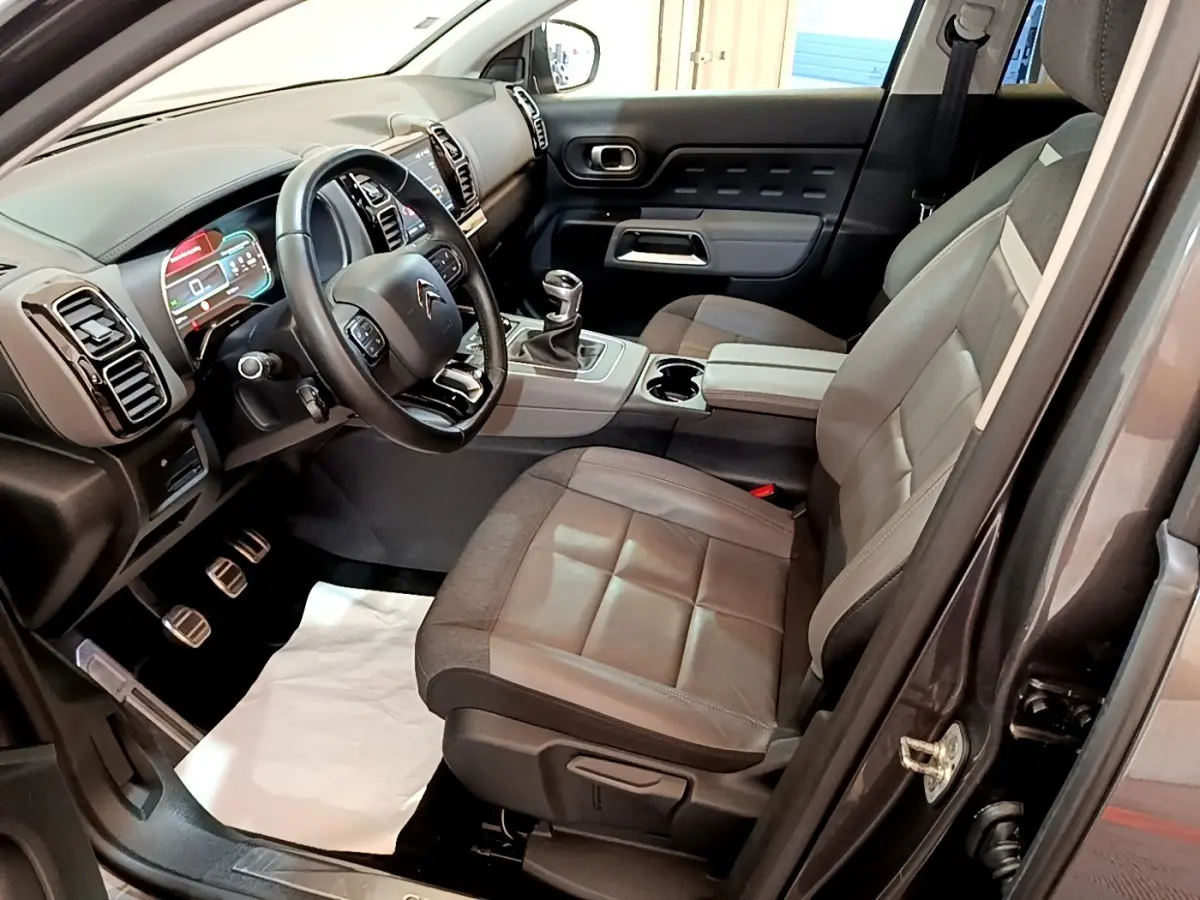 Vue intérieure côté conducteur du Citroën C5 Aircross gris foncé, avec volant cuir multifonctions et tableau de bord digital.