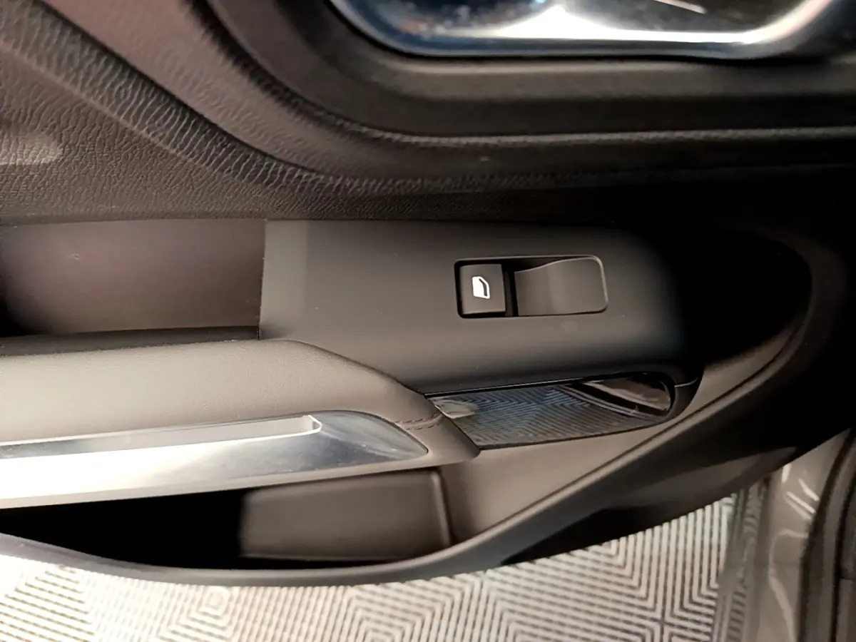 Détail de la commande de vitre côté conducteur sur porte intérieure noire du Citroën C5 Aircross gris foncé.