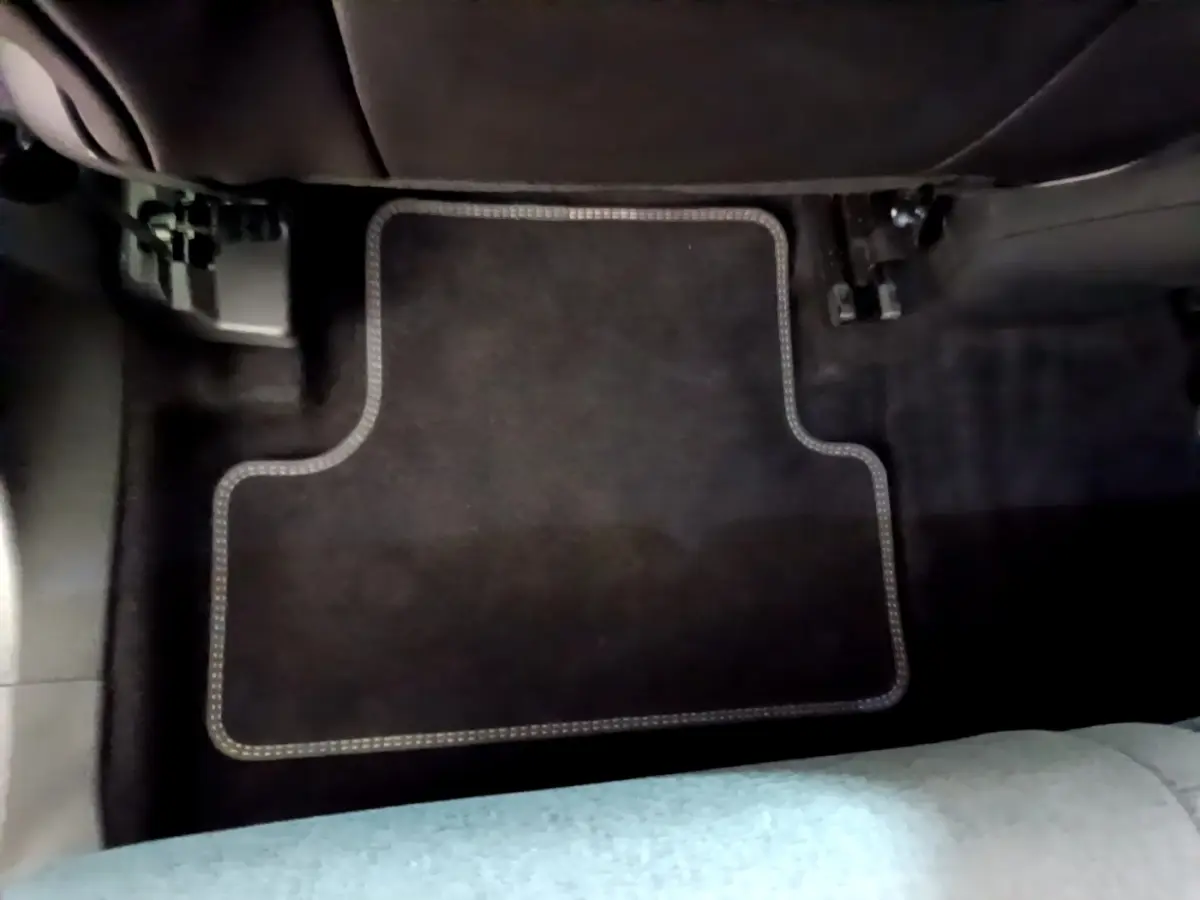 Vue rapprochée du tapis de sol noir avec surpiqûres claires à l'avant droit d'un Citroën C5 Aircross gris foncé.