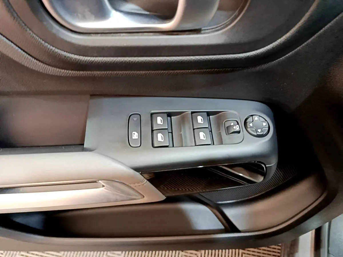 Gros plan sur la commande des vitres électriques côté conducteur du Citroën C5 Aircross gris foncé, intérieur noir.