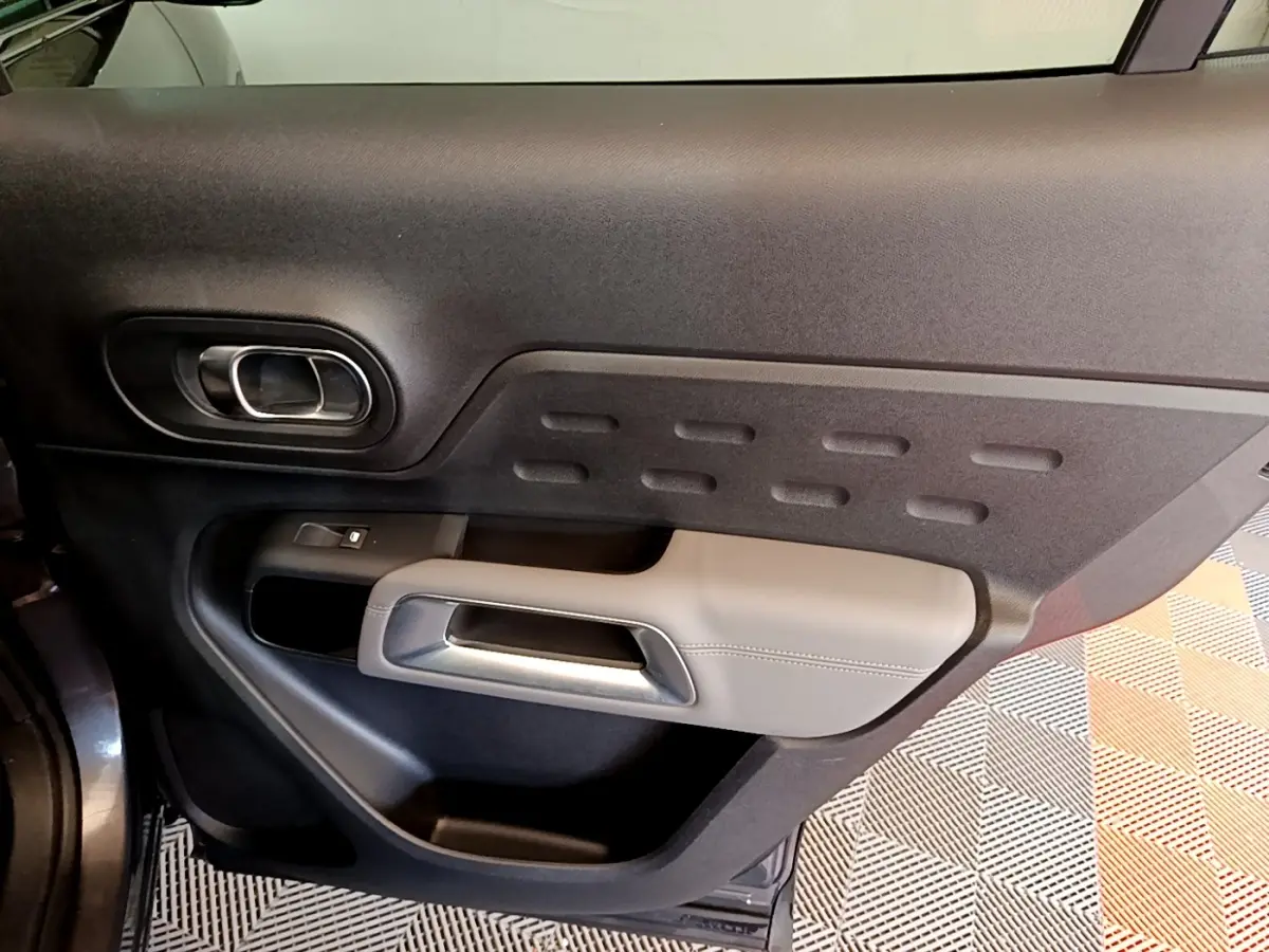 Vue intérieure de la porte avant gauche du Citroën C5 Aircross gris foncé, avec poignée argentée et garniture noire.