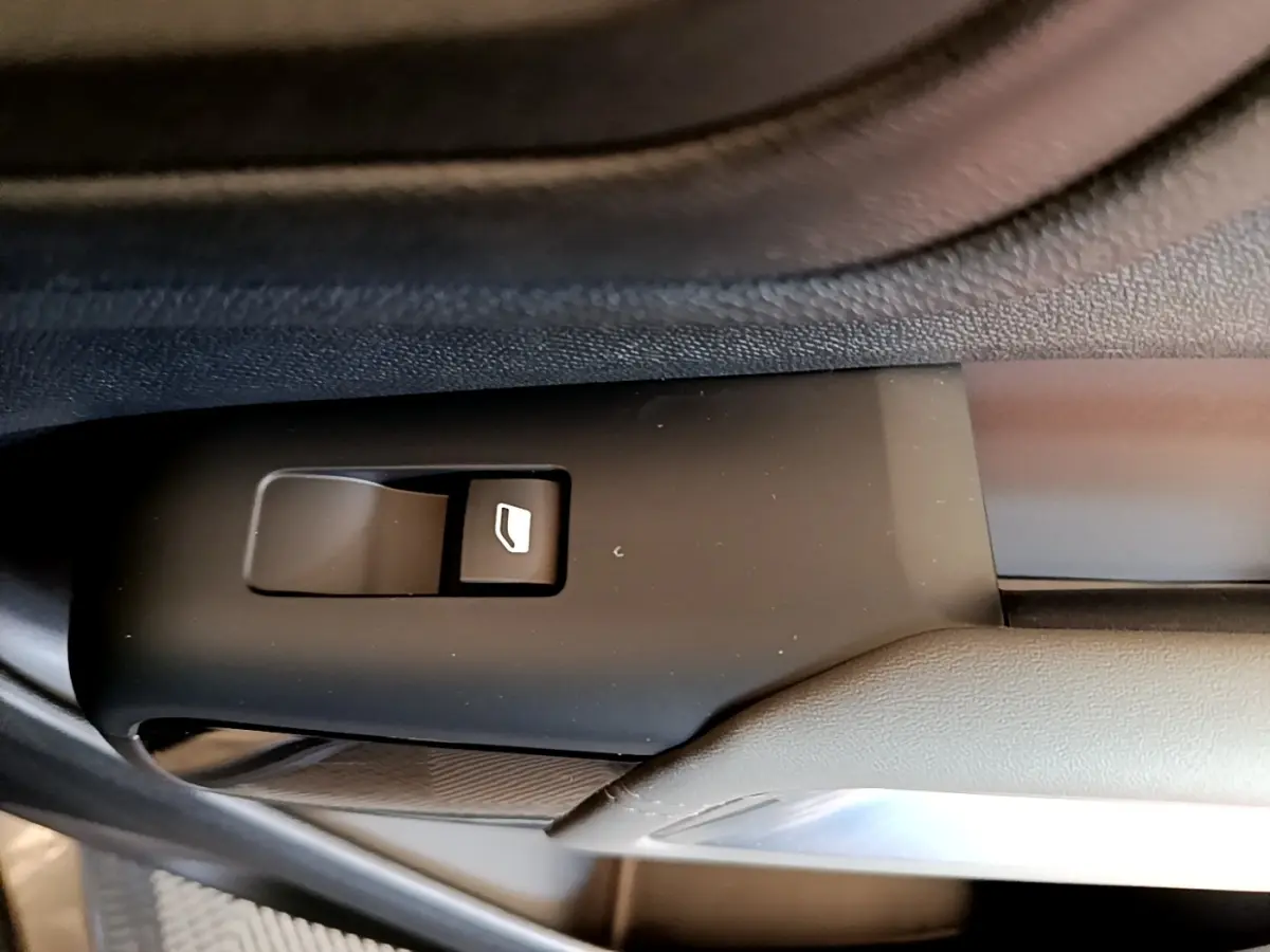 Gros plan sur l'interrupteur de lève-vitre côté conducteur dans l'habitacle noir du Citroën C5 Aircross gris foncé.