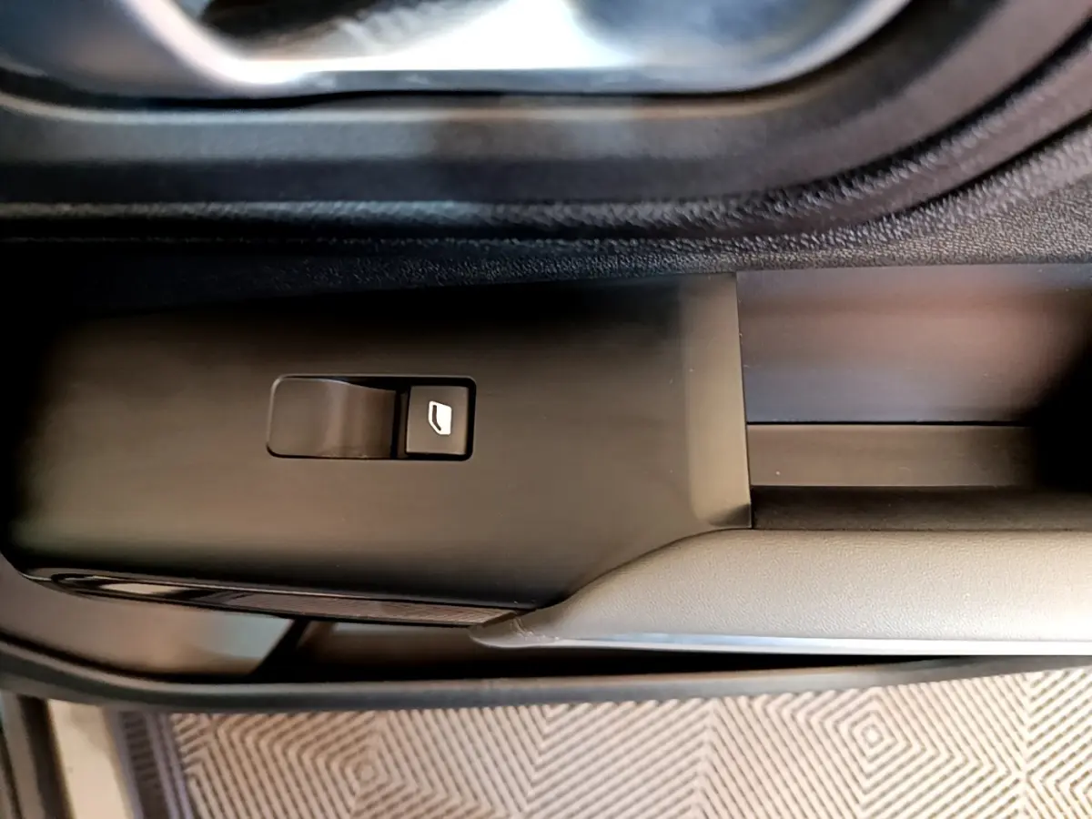 Gros plan sur le bouton de commande de la vitre électrique côté conducteur du Citroën C5 Aircross gris foncé.