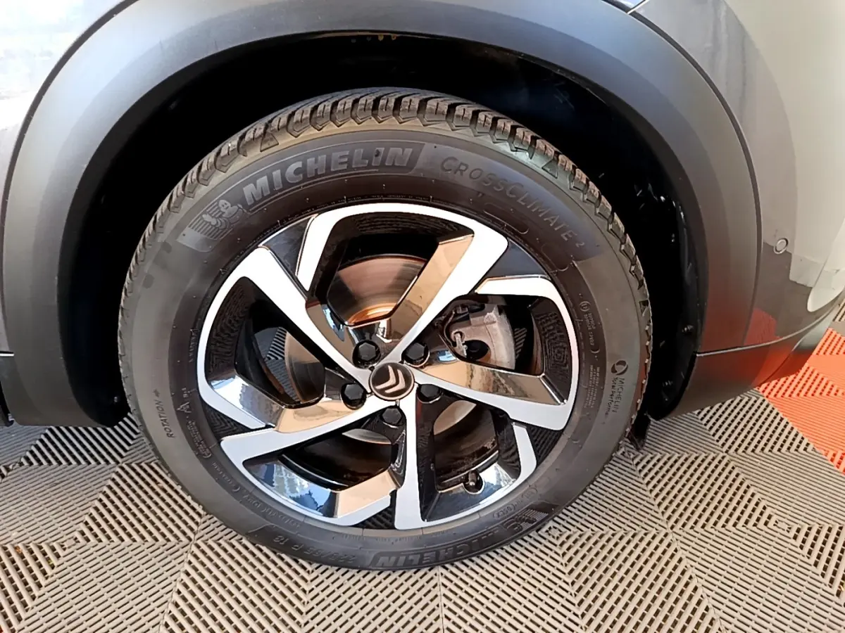 Gros plan sur la roue arrière droite d’un Citroën C5 Aircross gris foncé, avec pneu Michelin et passage de roue noir mat.