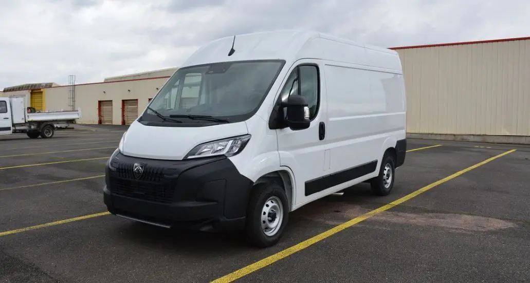 Vue 3/4 avant droit d'un utilitaire Peugeot Boxer Fourgon blanc Icy avec calandre noire et carrosserie haute.