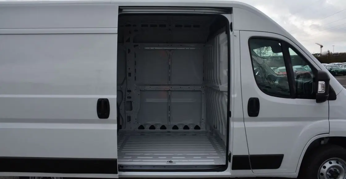 Vue latérale droite du Peugeot Boxer Fourgon blanc Icy avec porte coulissante ouverte montrant l’espace de chargement vide.