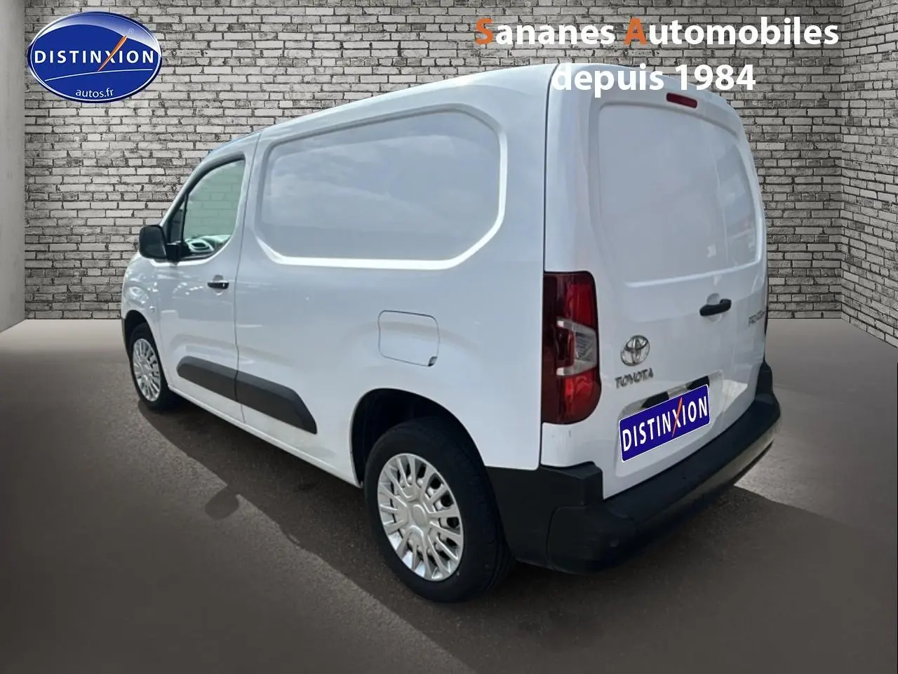 Vue 3/4 arrière droite d'un Toyota Proace City blanc 2023 avec porte latérale tôlée et coques de rétroviseurs noires.