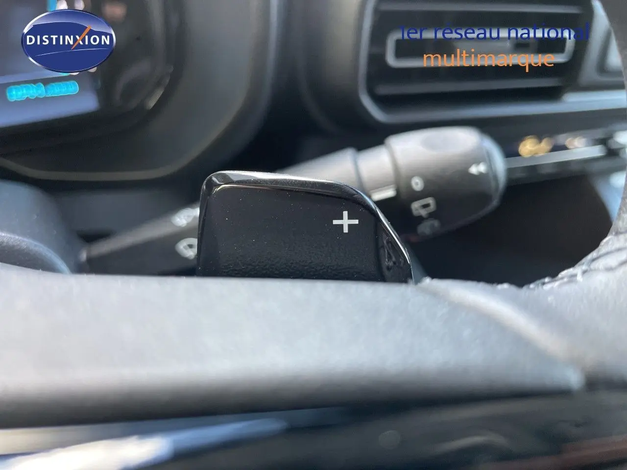 Gros plan sur la palette de changement de vitesse "+" derrière le volant d'un Citroën Berlingo noir, intérieur moderne.