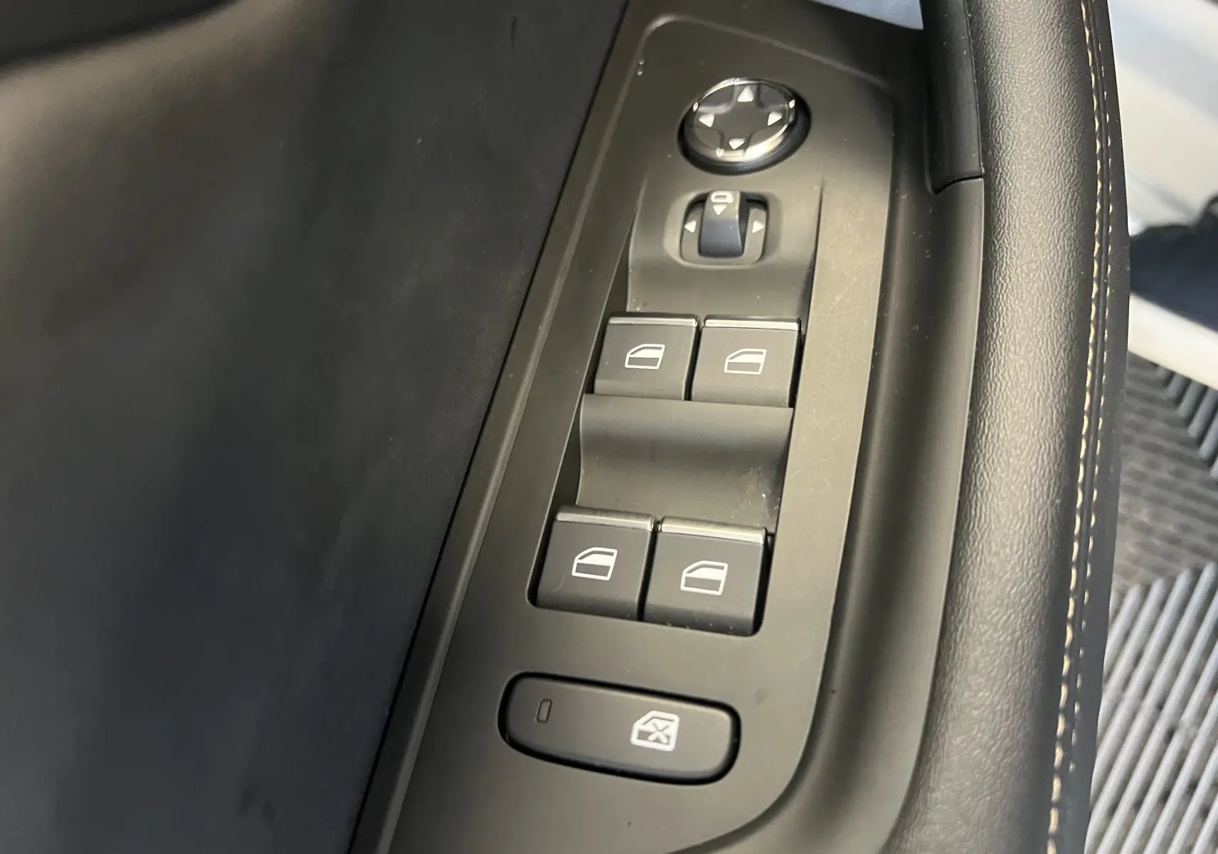 Gros plan sur les commandes de lève-vitres côté conducteur du Peugeot 508 SW blanc 2024, finition GT.