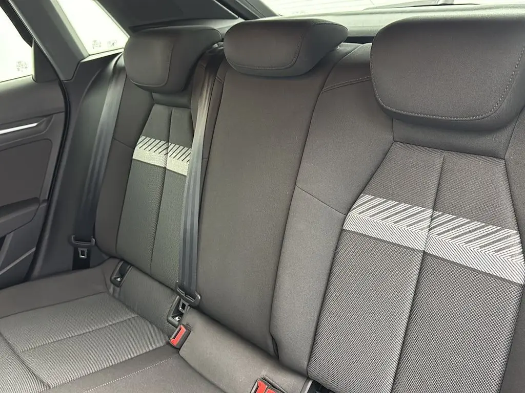 Vue intérieure des sièges arrière de l'Audi A3 Sportback 2021, tissu gris avec motif chevrons et ceintures de sécurité.