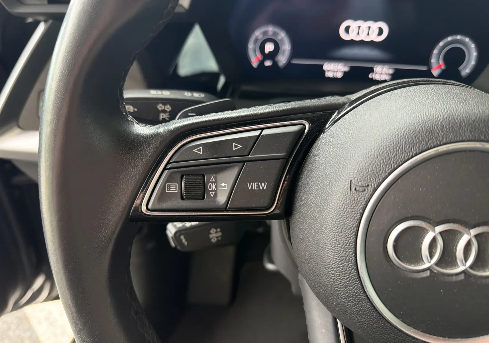 Gros plan sur le volant noir de l'Audi A3 Sportback 2021 avec commandes intégrées et tableau de bord digital.