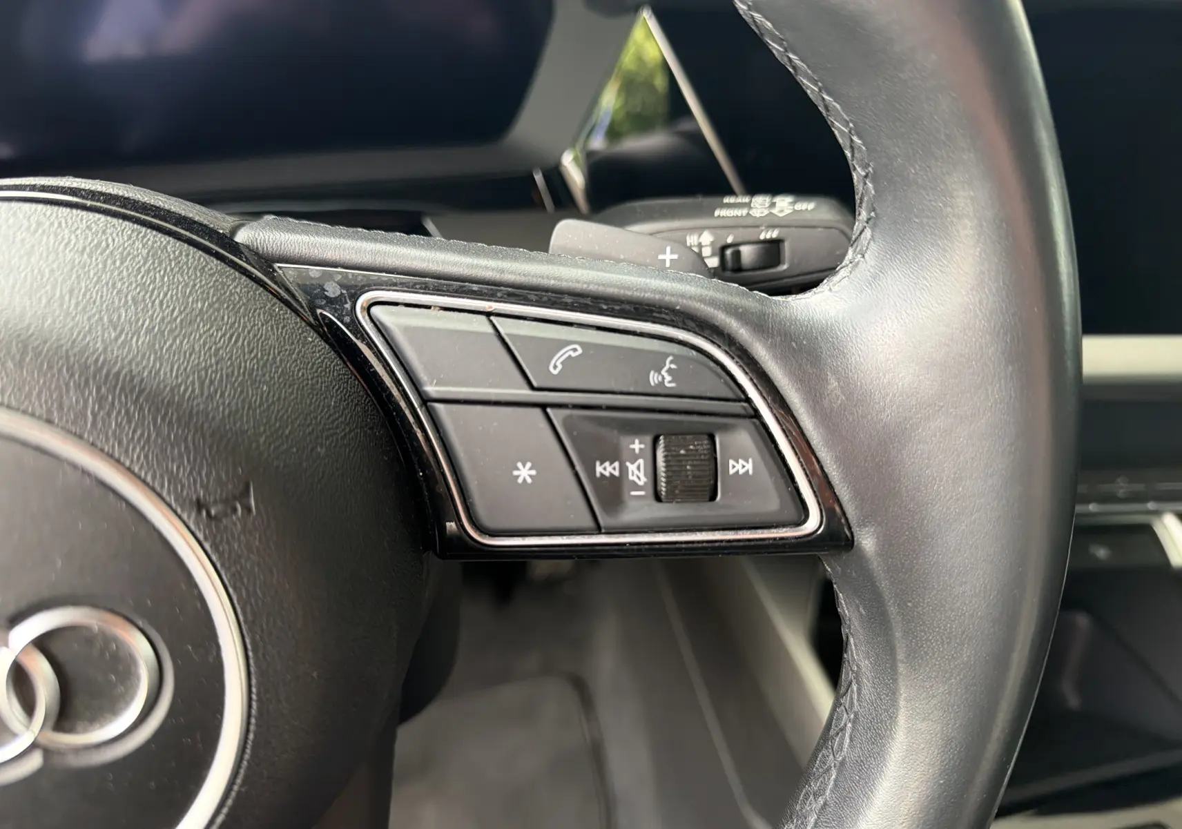 Gros plan sur les commandes à droite du volant en cuir noir de l'Audi A3 Sportback 2021, finition Design, intérieur moderne.