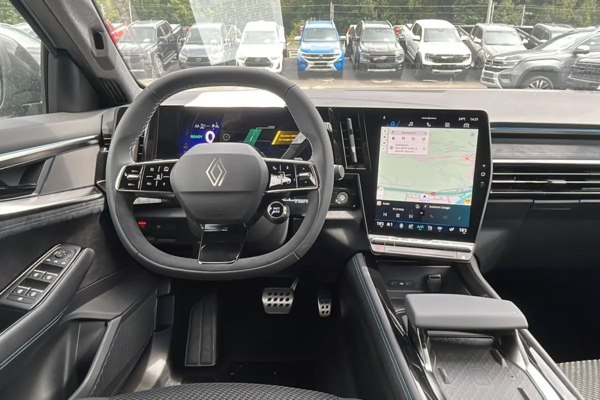 Vue intérieure avant du Renault Austral gris schiste, volant multifonctions et écran tactile central avec navigation visible.