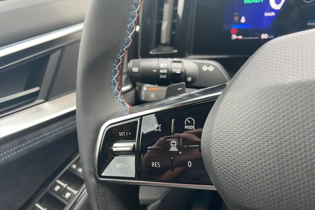 Gros plan sur le volant cuir multifonctions du Renault Austral New 200 Esprit Alpine, avec surpiqûres bleues et rouges.