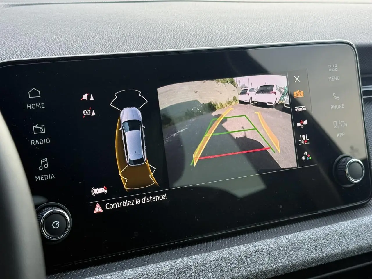 Écran intérieur affichant la caméra de recul et l’aide au stationnement d’une Skoda Scala noire Magic Perle.
