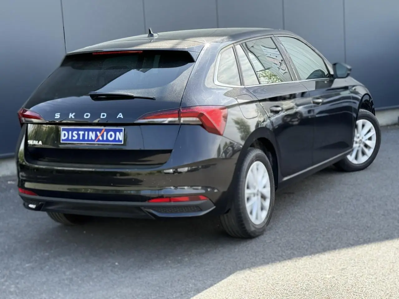 Vue 3/4 arrière droite d'une Skoda Scala noire Magic Perle avec jantes alliage 16 pouces et vitres surteintées.
