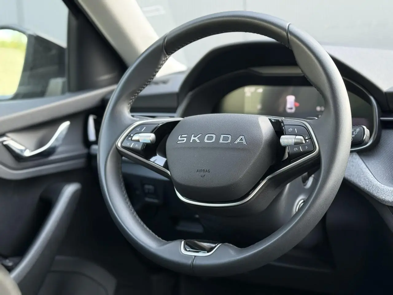 Gros plan sur le volant cuir multifonctions Skoda noir à deux branches dans l'habitacle côté conducteur.