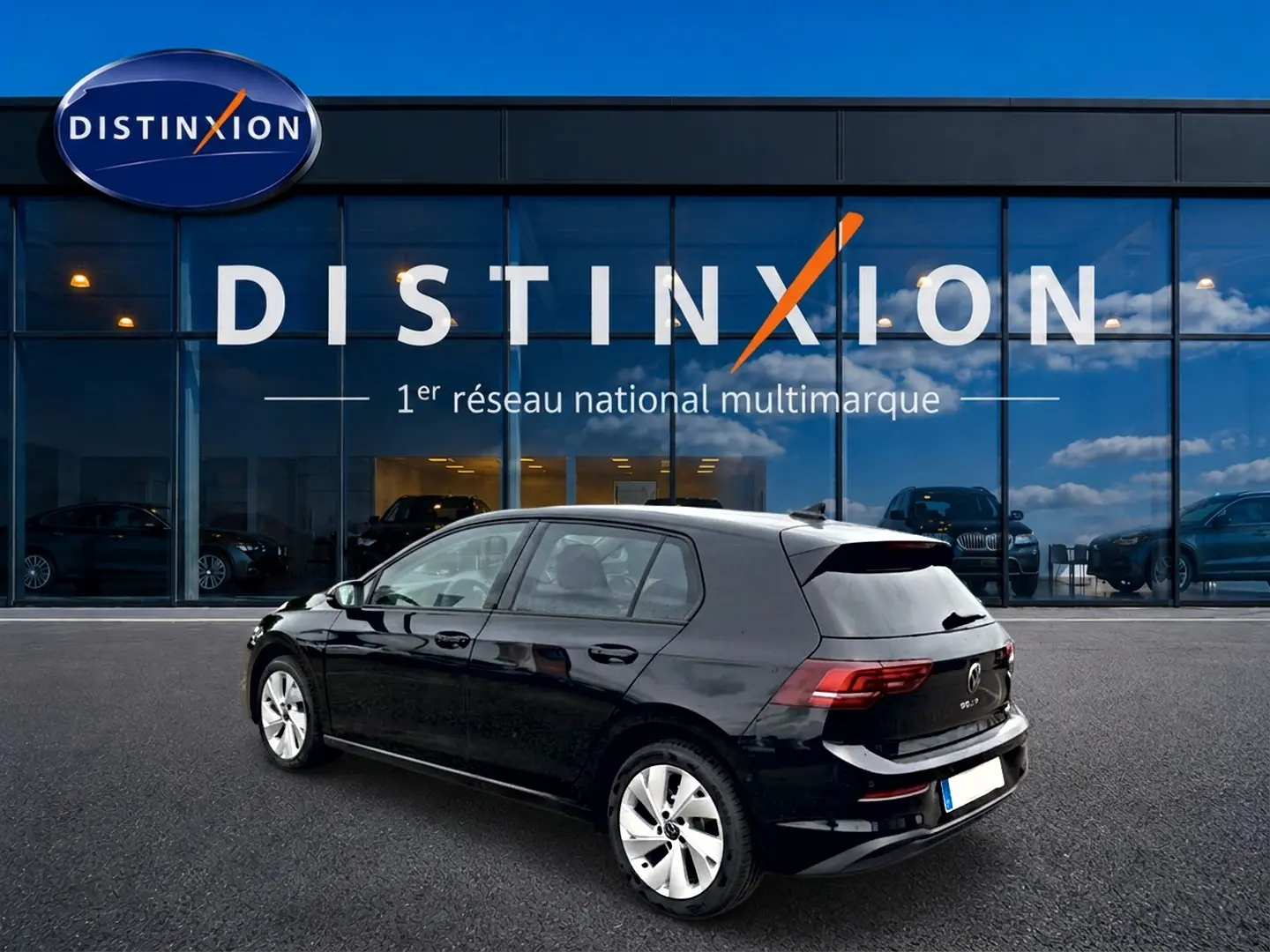 Vue 3/4 arrière droite d'une Volkswagen Golf noire 2026 garée devant une vitrine Distinxion.