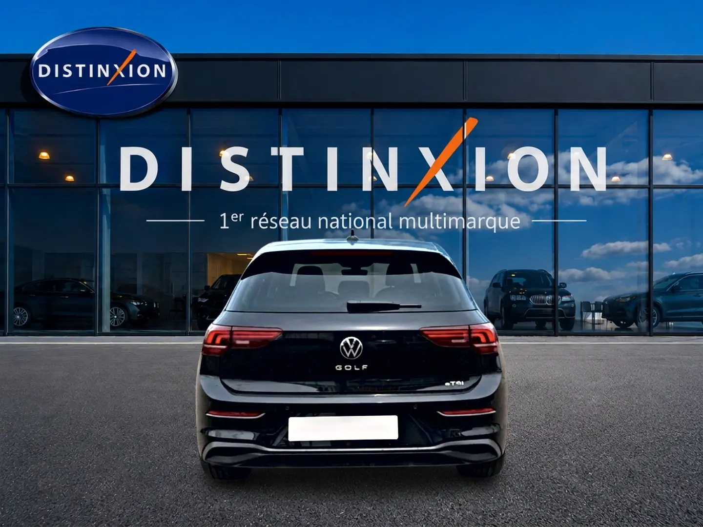 Vue arrière d'une Volkswagen Golf noire 2026 garée devant une vitrine avec logo Distinxion visible.