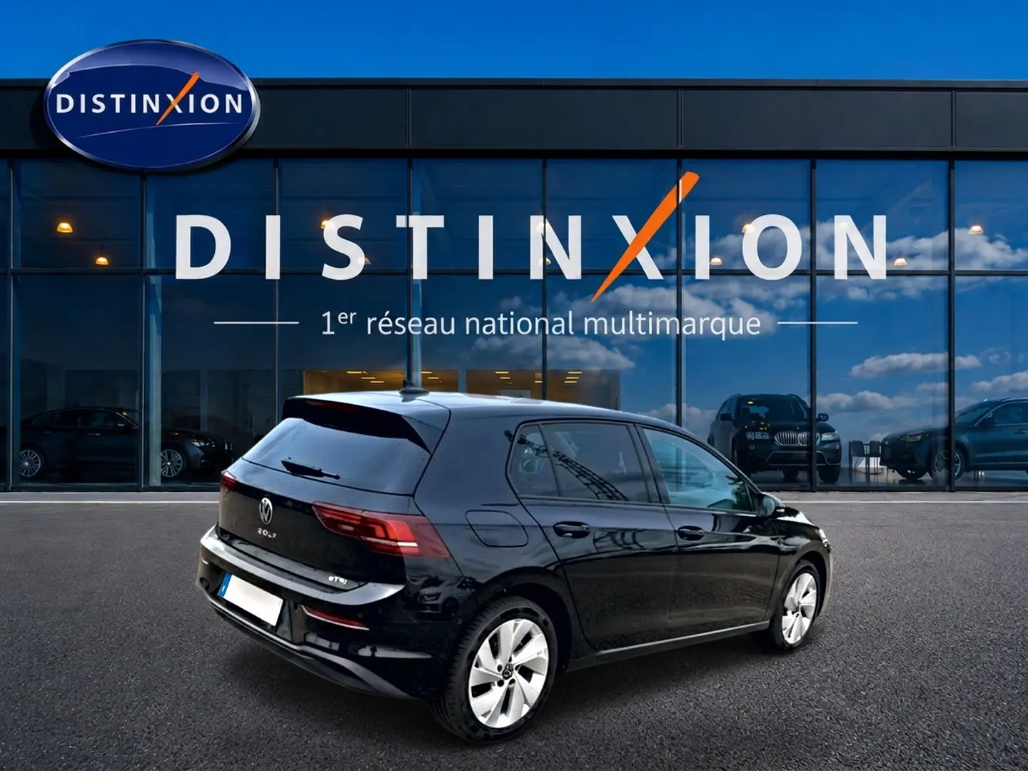 Vue 3/4 arrière droite d'une Volkswagen Golf 1.5 ETSI Evo2 noire garée devant une vitrine Distinxion.