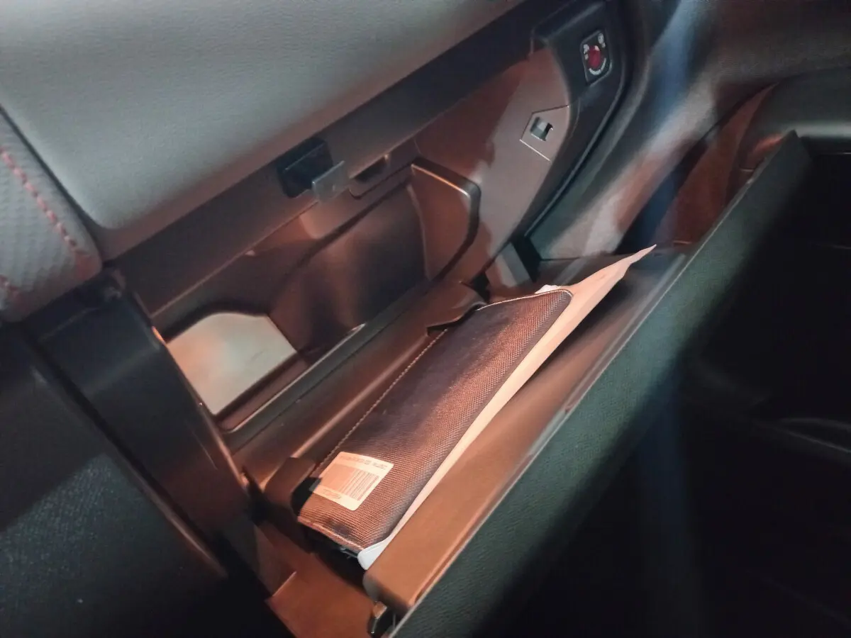 Gros plan de la boîte à gants ouverte du Citroën C5 Aircross blanc 2020, montrant un manuel dans un étui noir.