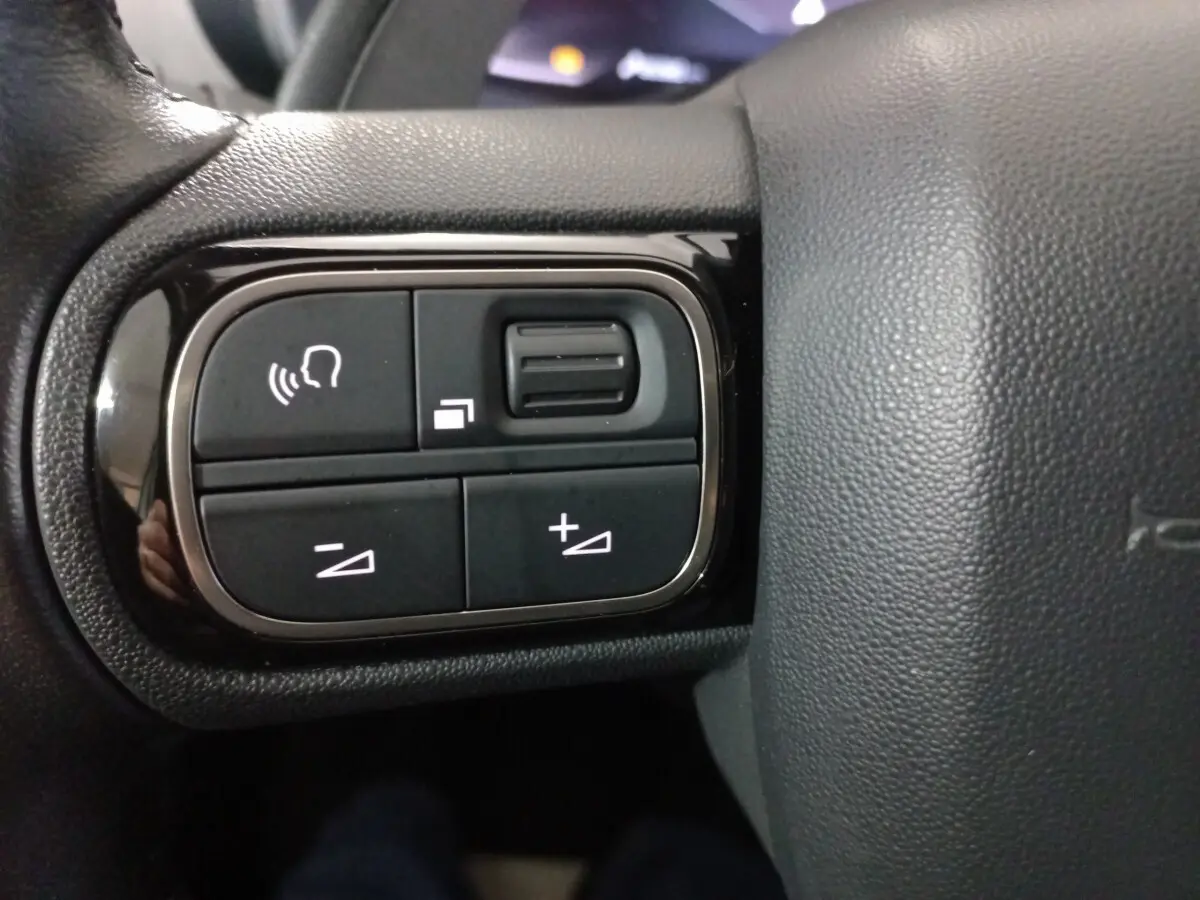 Gros plan sur les commandes vocales et volume sur le volant cuir noir du Citroën C5 Aircross blanc 2020.