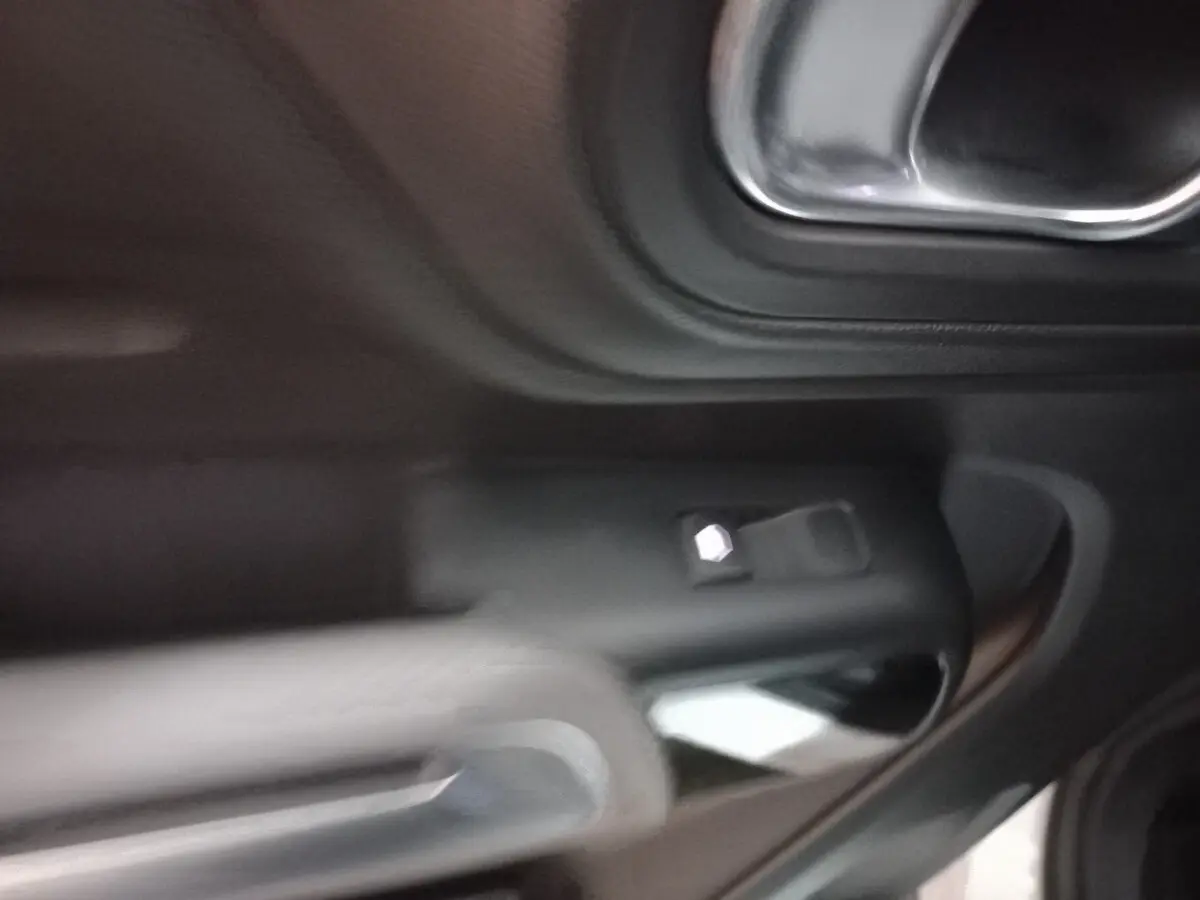Détail de la poignée intérieure côté gauche d'une Citroën C5 Aircross 2020 avec commandes de vitre noire.