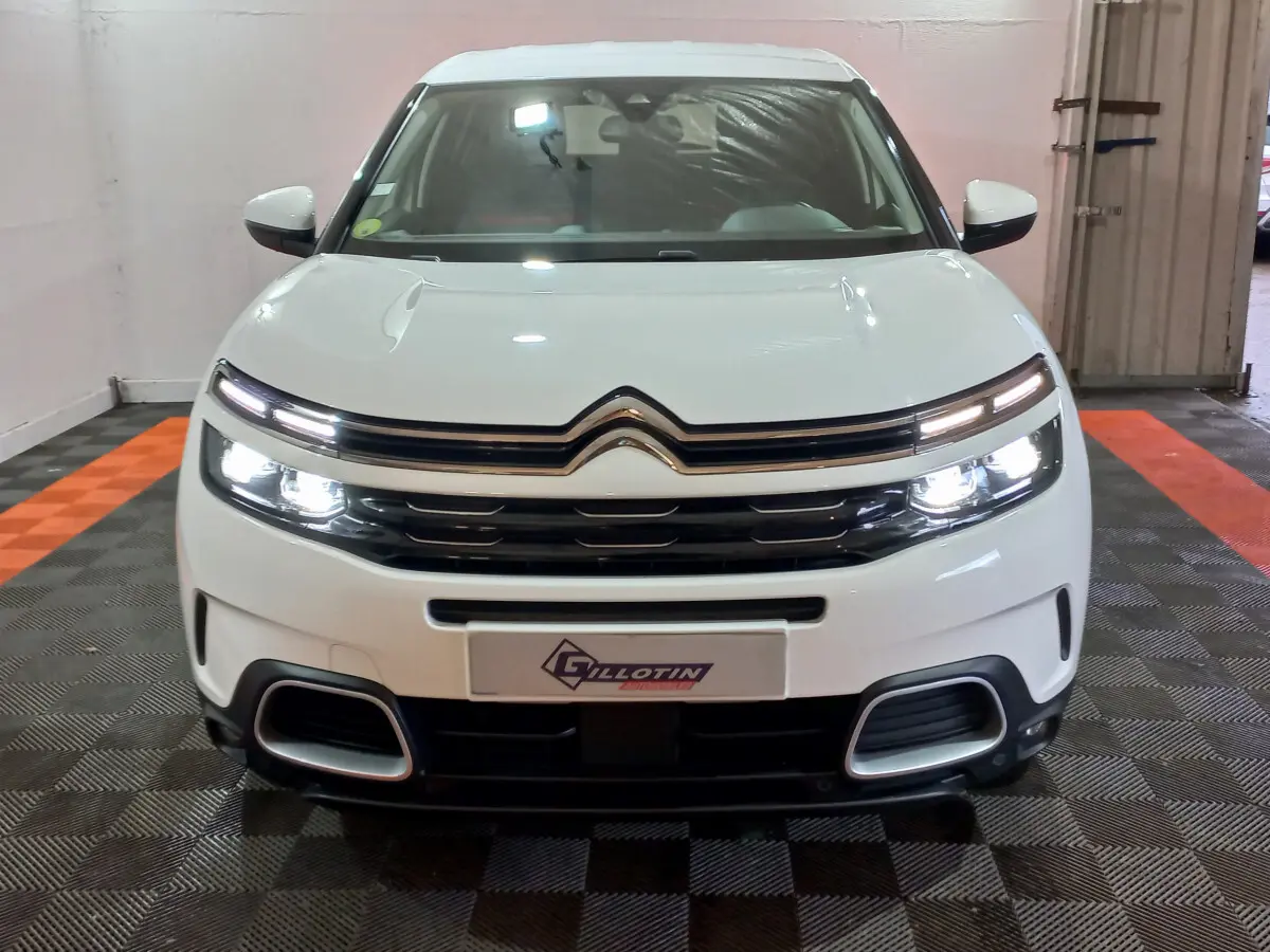 Vue frontale d'un Citroën C5 Aircross blanc avec phares LED allumés et calandre noire distinctive.