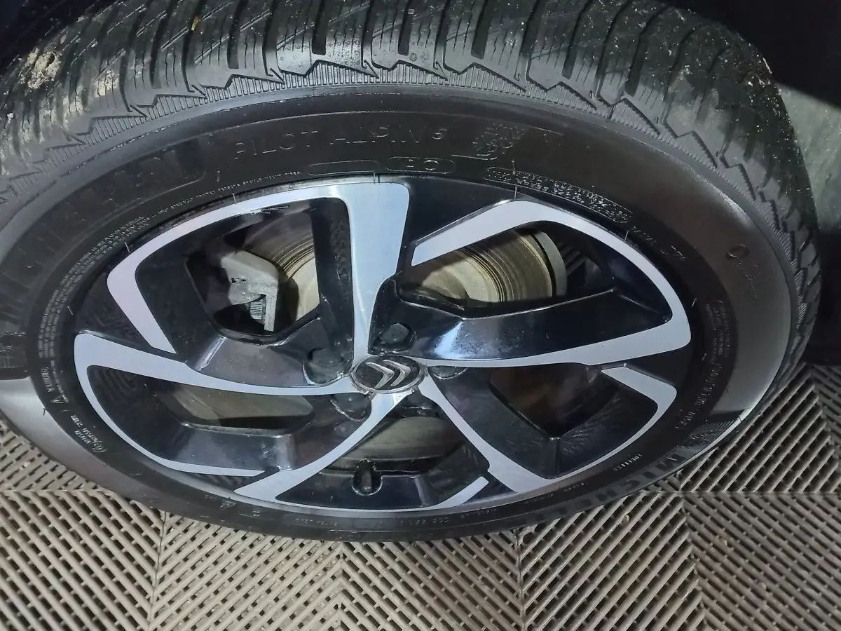 Gros plan sur la jante noire et argentée avec logo Citroën d'un Citroën C5 Aircross blanc, vue latérale.