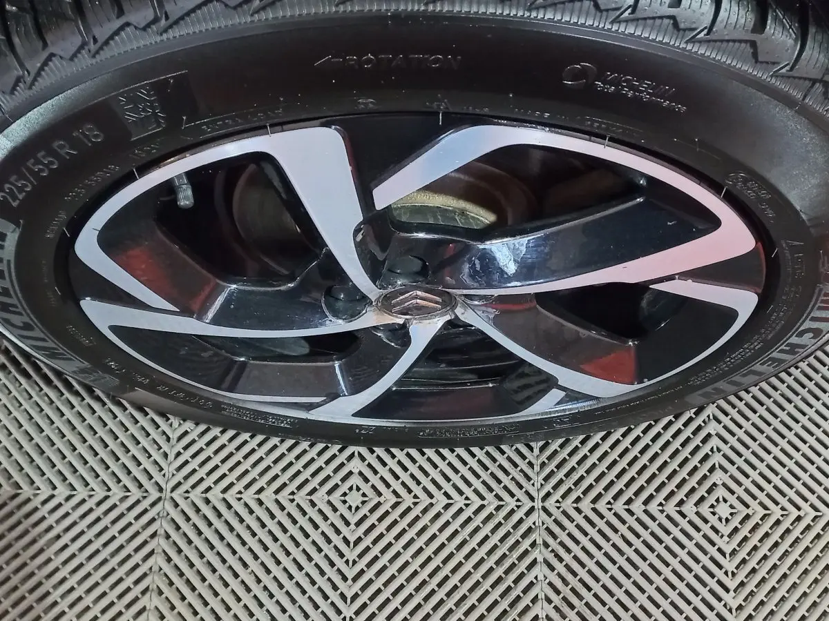 Gros plan sur la jante noire et argentée d'une Citroën C5 Aircross blanche, mettant en valeur le logo central distinctif.