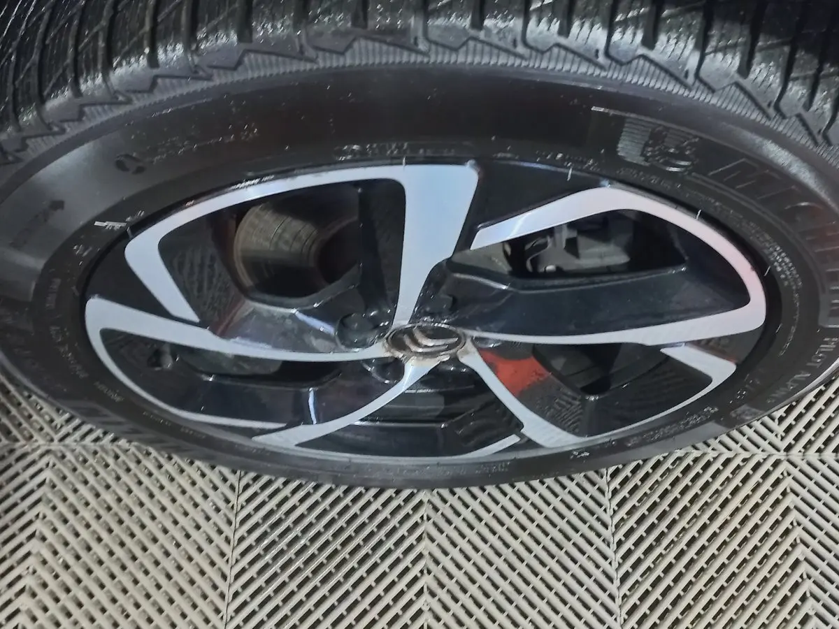 Gros plan sur la jante noire et argentée d'une Citroën C5 Aircross blanche, mettant en valeur le logo central Citroën.