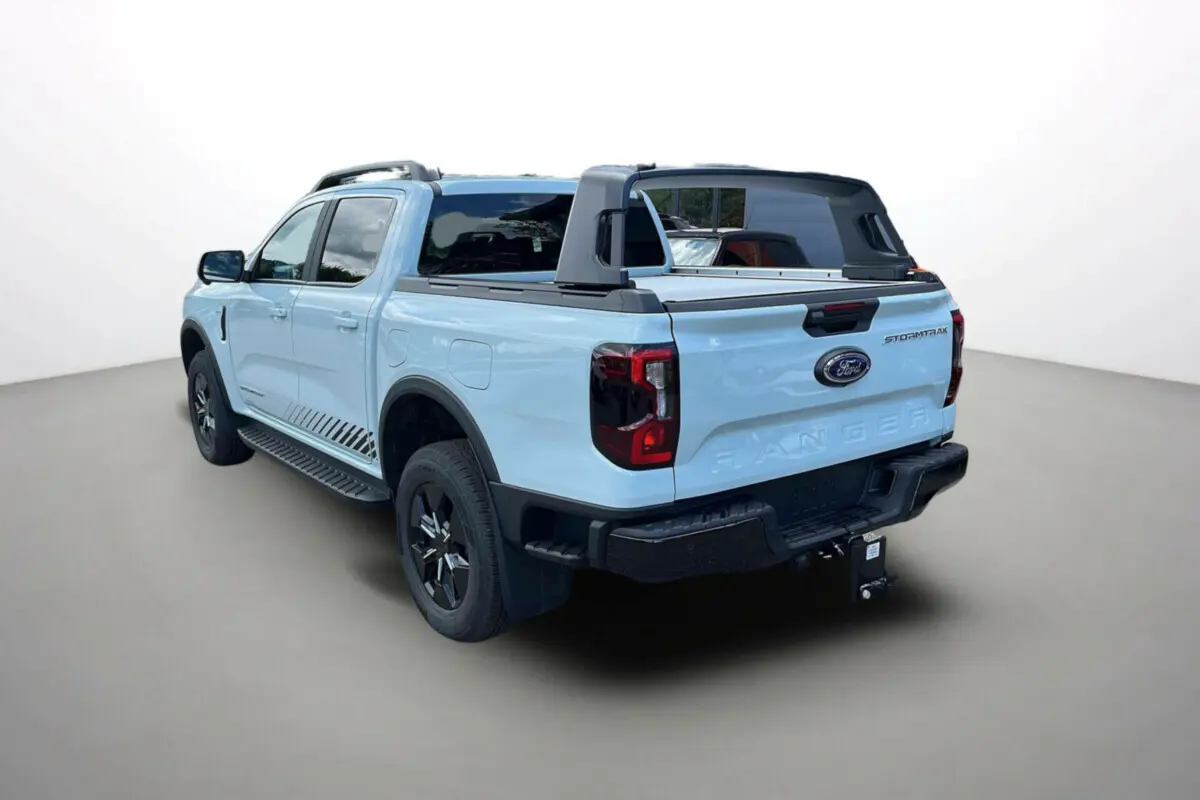 Ford Ranger Stormtrak 2026 vue 3/4 arrière droit, couleur bleu clair avec arceau sport et attelage visible.