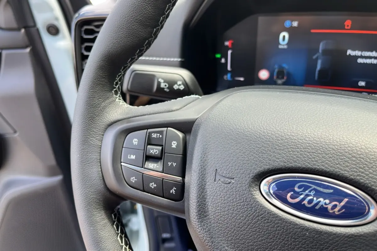 Gros plan sur le volant cuir multifonctions du Ford Ranger gris zen, avec commandes intégrées et tableau de bord numérique en arrière-plan.