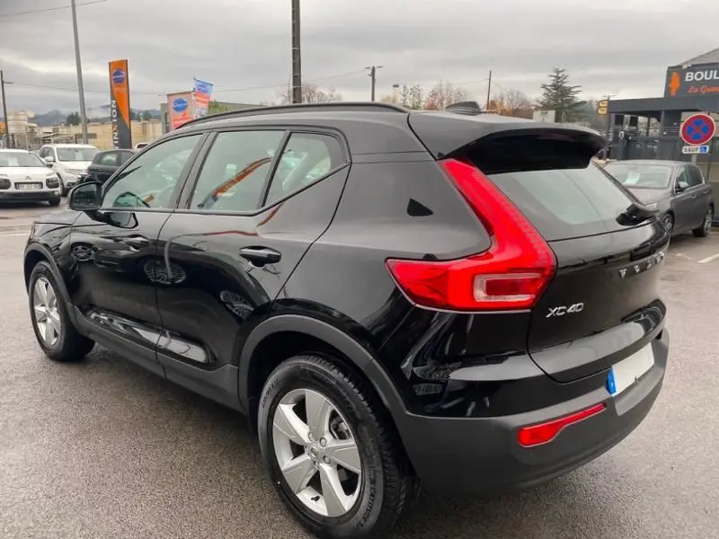 Vue 3/4 arrière droite d'un Volvo XC40 noir solid, soulignant ses feux arrière en forme de C et ses jantes argentées.