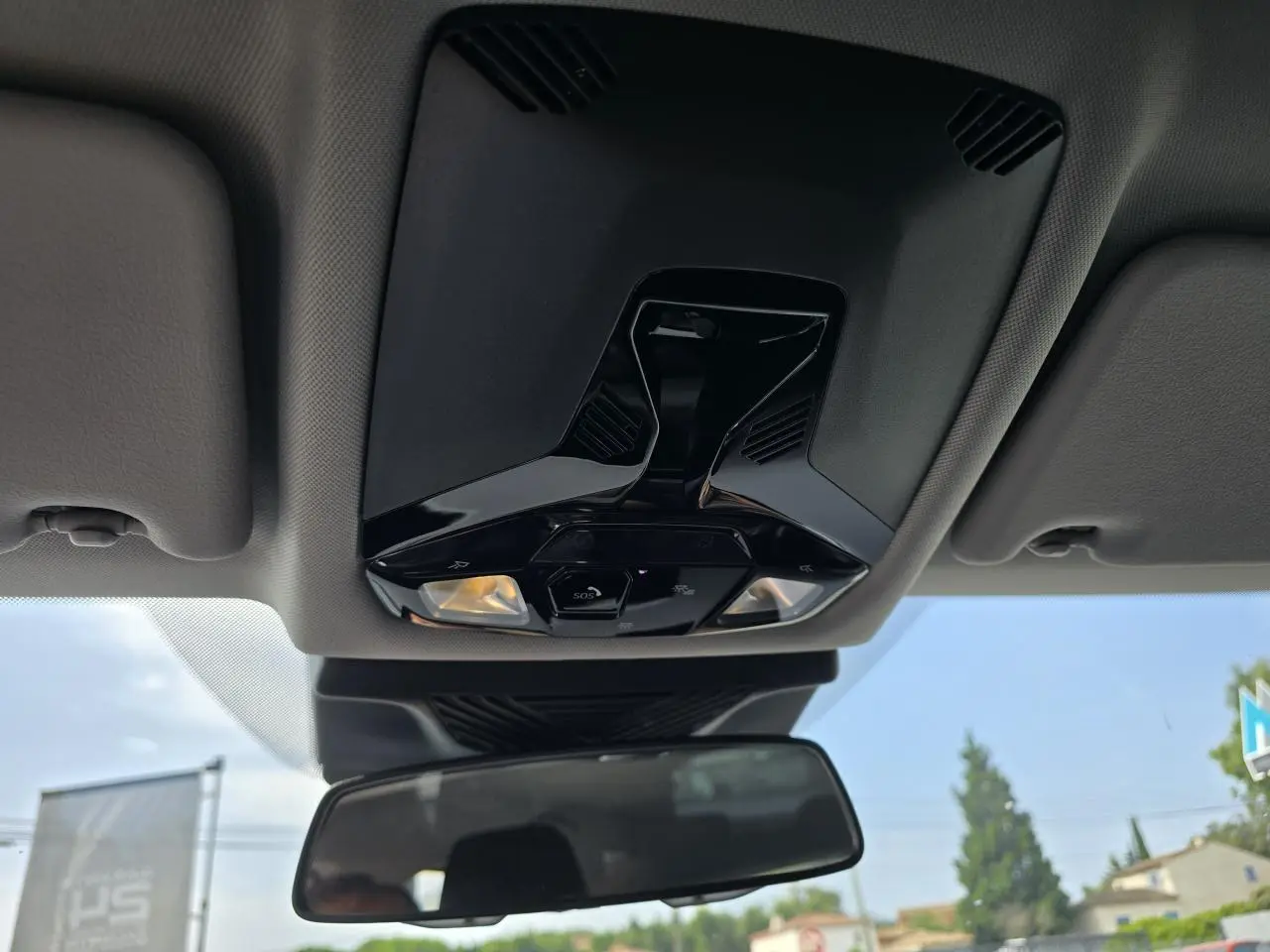 Plafonnier avec commandes et éclairages intégrés au-dessus du rétroviseur intérieur d'une BMW Série 1 gris Skyscraper.