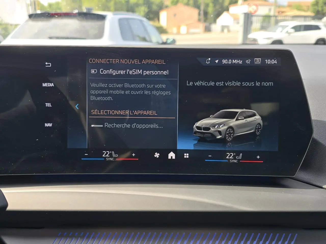 Écran incurvé BMW Live Cockpit affichant une BMW Série 1 gris Skyscraper vue en 3/4 avant droit.