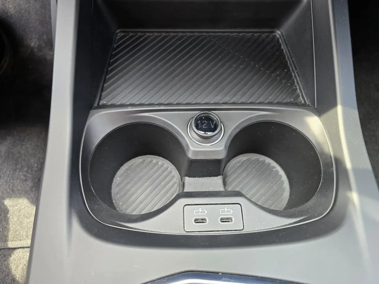 Gros plan sur la console centrale noire de la BMW Série 1 120D M Sport avec deux porte-gobelets et deux ports USB-C.