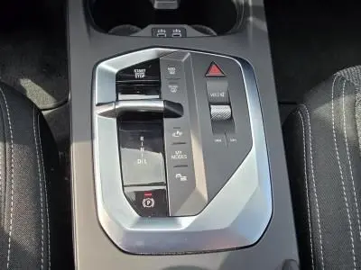Gros plan sur la console centrale grise de la BMW Série 1 F70, montrant les commandes de boîte auto et les boutons multifonctions.