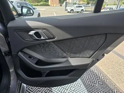 Vue rapprochée de la porte intérieure côté gauche de la BMW Série 1 F70 gris Skyscraper avec garniture tissu anthracite et commandes électriques.