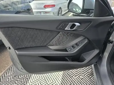 Intérieur de la porte côté gauche de la BMW Série 1 F70 gris Skyscraper, avec commandes électriques et garniture tissu anthracite.